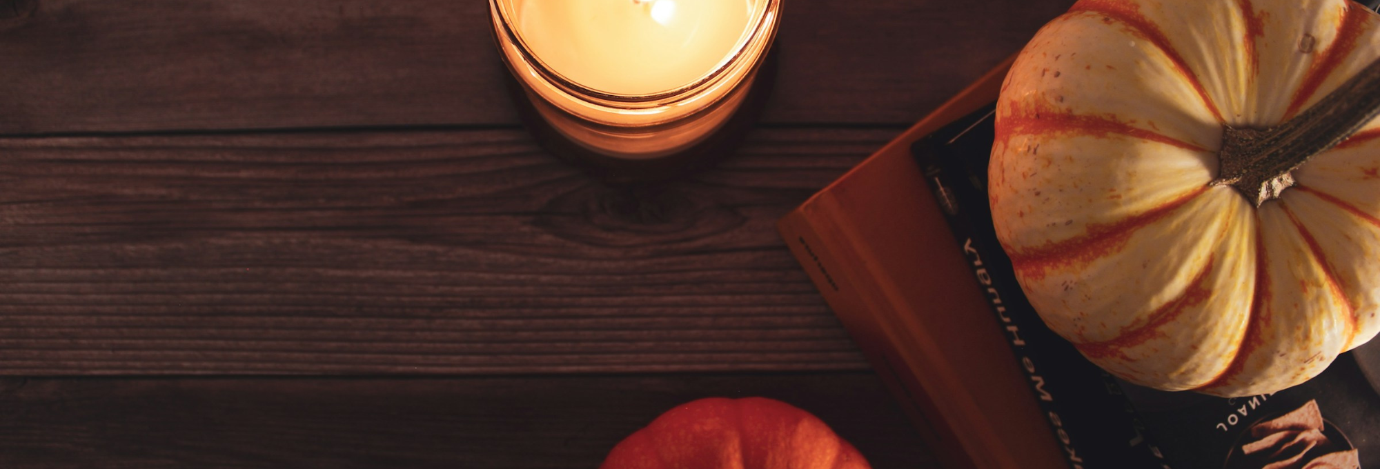 Thanksgiving pumpkin and candle on a hardwood floor